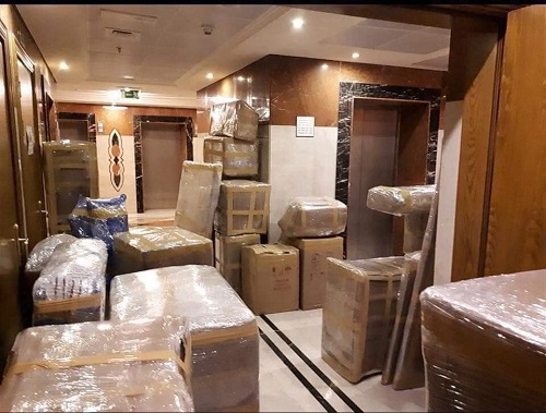 Fully wrapped furniture and cartons staged in a hallway before loading